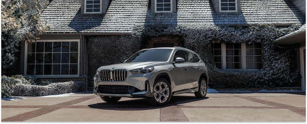 Silver 2026 BMW X1 parked on a residential driveway, front three-quarter view.