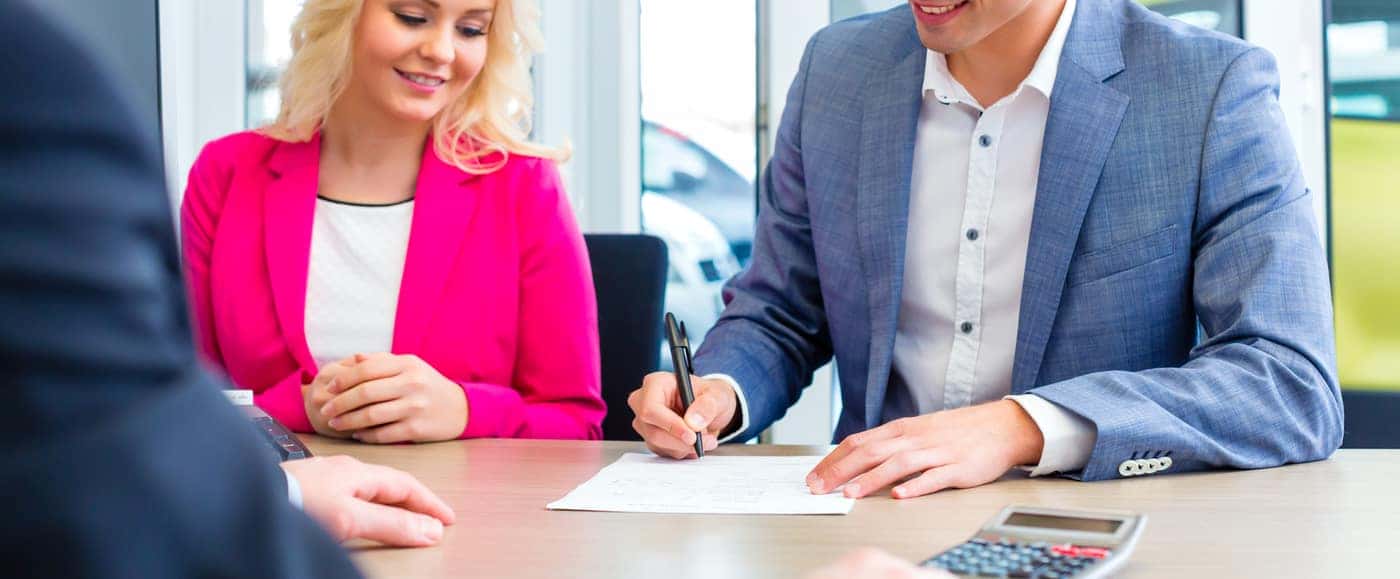 Man signing sales contract for auto at car dealership
