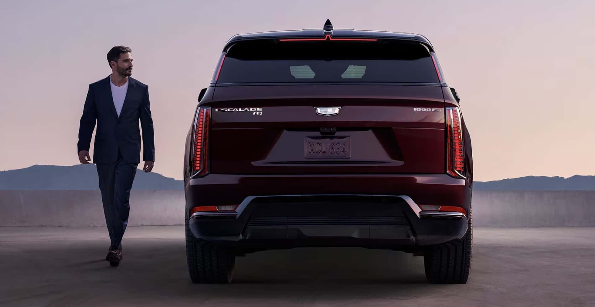 2026 Cadillac Escalade IQ Luxury SUV Rear View with Businessman Carrying Briefcase for sale at Covert Cadillac, Austin, Texas