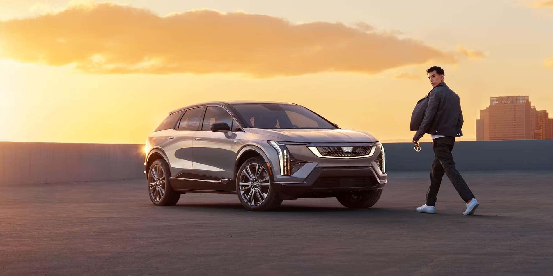2027 Cadillac OPTIQ in silver, front passenger side, with owner alongside