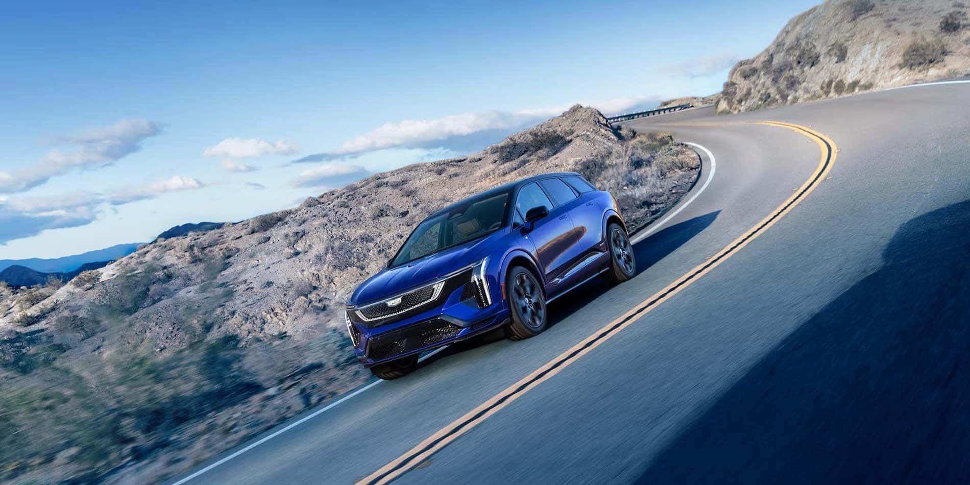 2026 Cadillac OPTIQ-V in blue, driving a mountain road, at Covert Cadillac Bee Cave in Austin