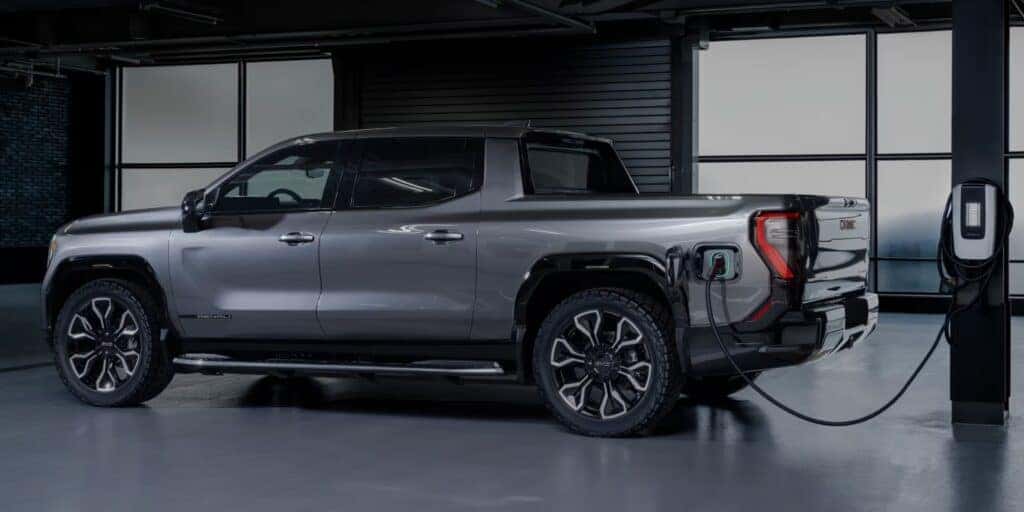 gray 2025 GMC Sierra EV Denali truck charging in a modern garage