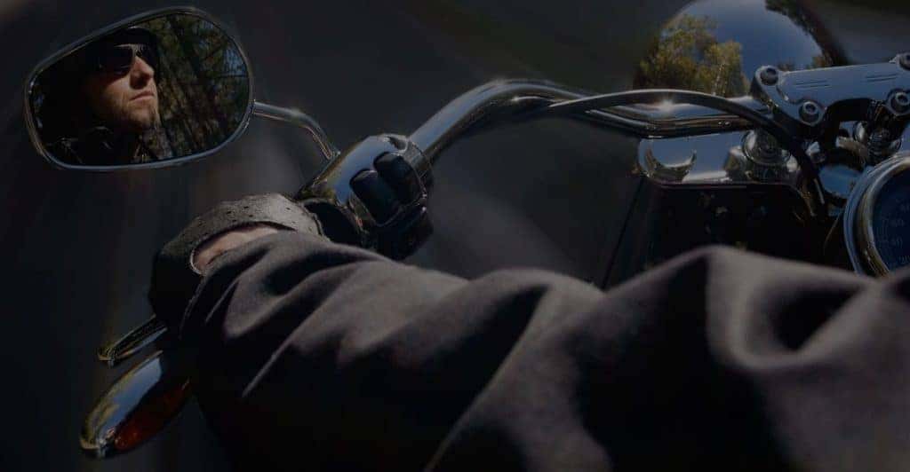 looking over shoulder of Harley Davidson driver viewing a profile of his face in side mirror
