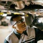 Lexus service technician inspecting under Lexus undercarriage