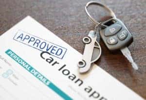 A close up shot of the top of automotive loans papers with car keys laying on top of them.