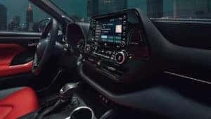 A close up of the 2021 Toyota Highlander's infotainment system in the dark so it illuminates the cabin while someone drives the vehicle.