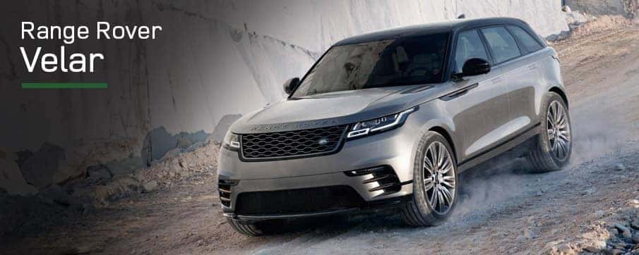 A tan Land Rover Range Rover Velar driving down hill on a dirt road