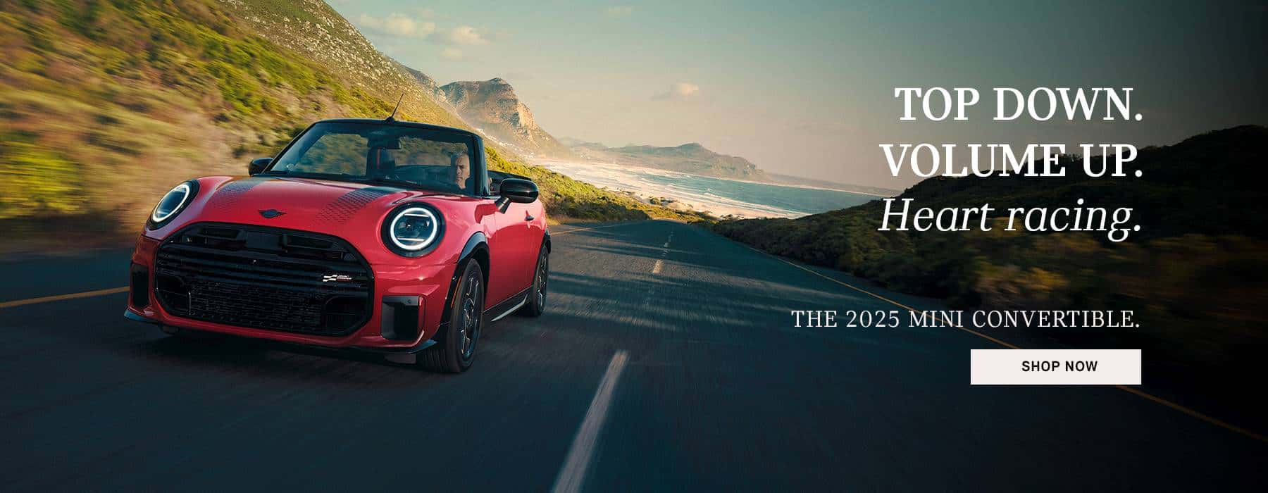 Red JCW Convertible driving between mountains.