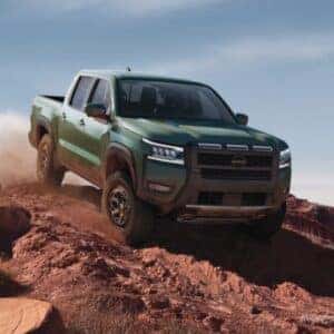 2025 Nissan Frontier driving over dirt hill