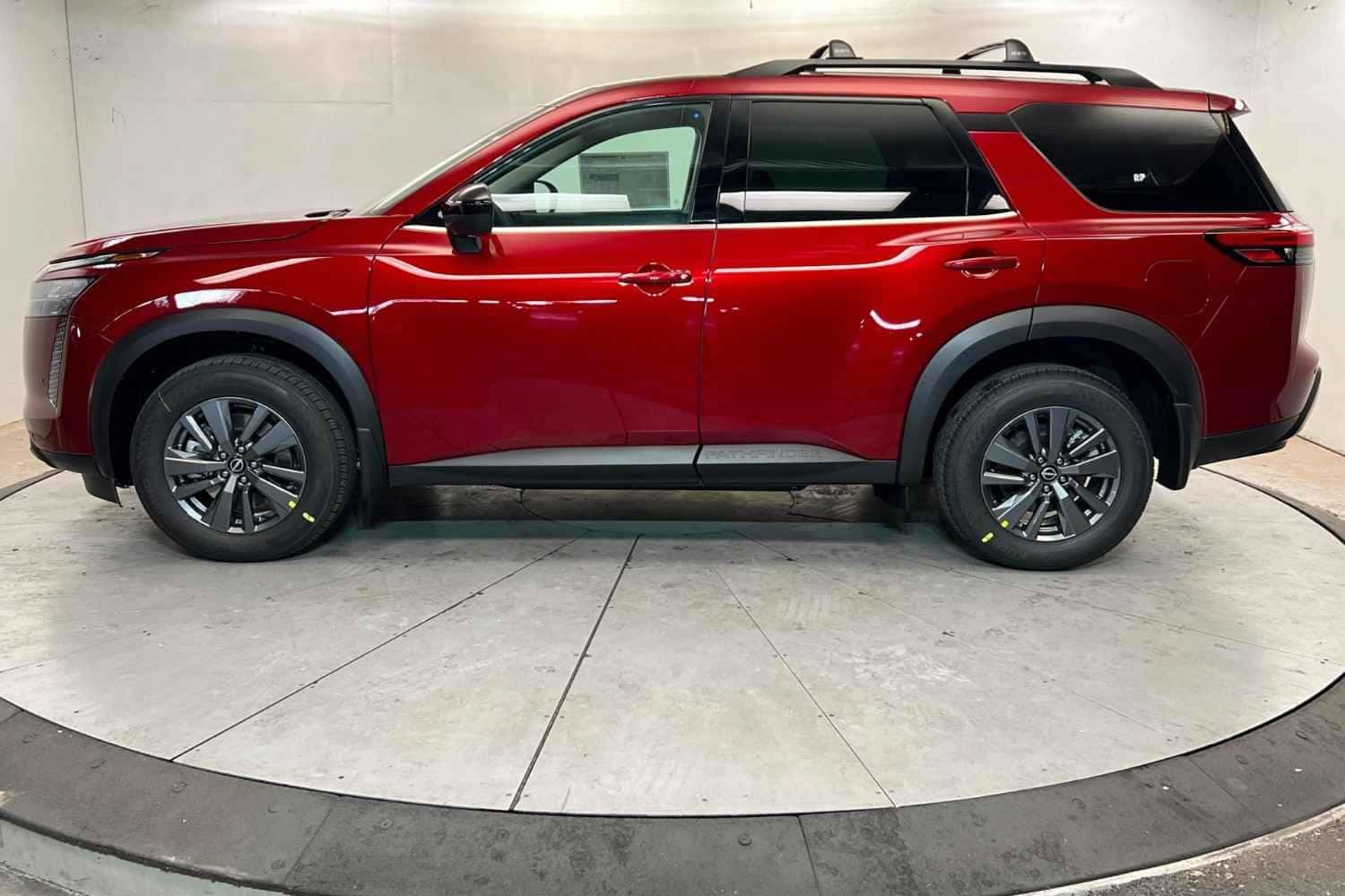 Red Nissan Pathfinder side view at Stephen Wade Nissan showroom in St. George, Utah