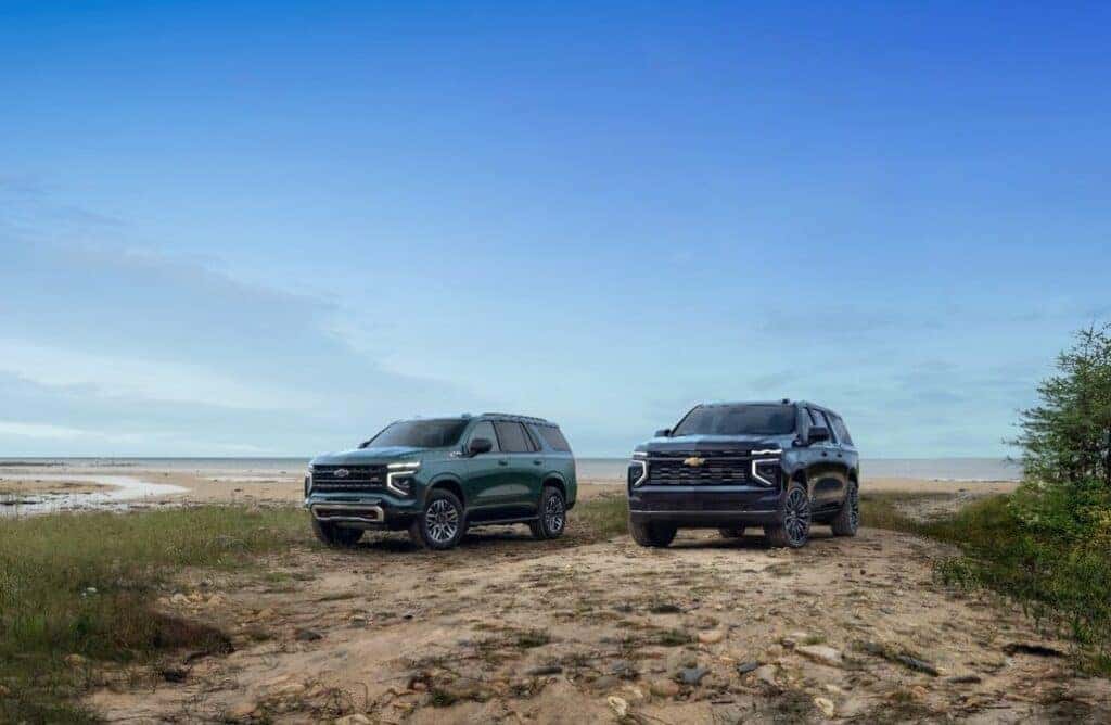 Group shot of 2025 Tahoe Z71 (left) and 2025 Suburban High Country shown on the beach