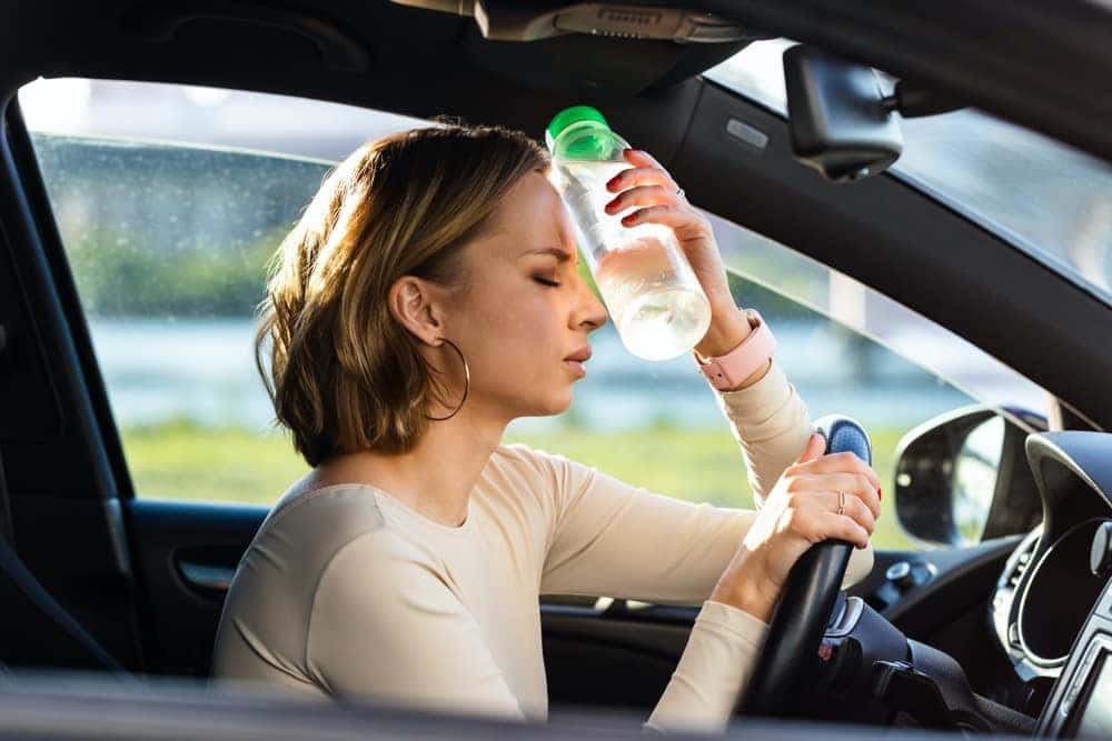 Womens AC is Broken and needs repair so she is holding a cold water bottle to her head