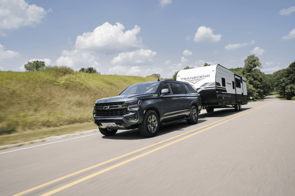 Chevrolet Suburban Towing a Camper on a Rural Road 3/4 View