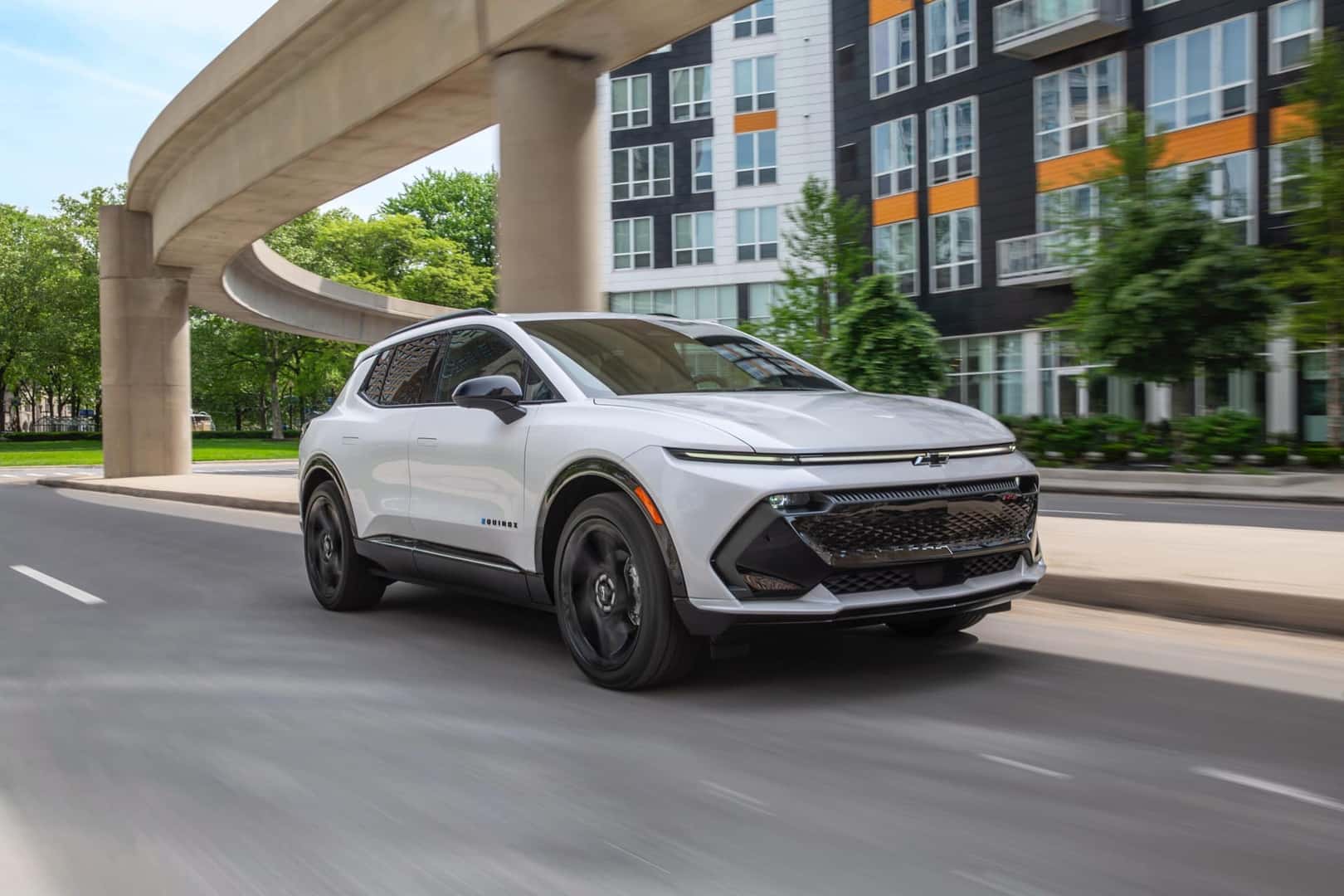 Chevy Equinox EV in white driving through the city.