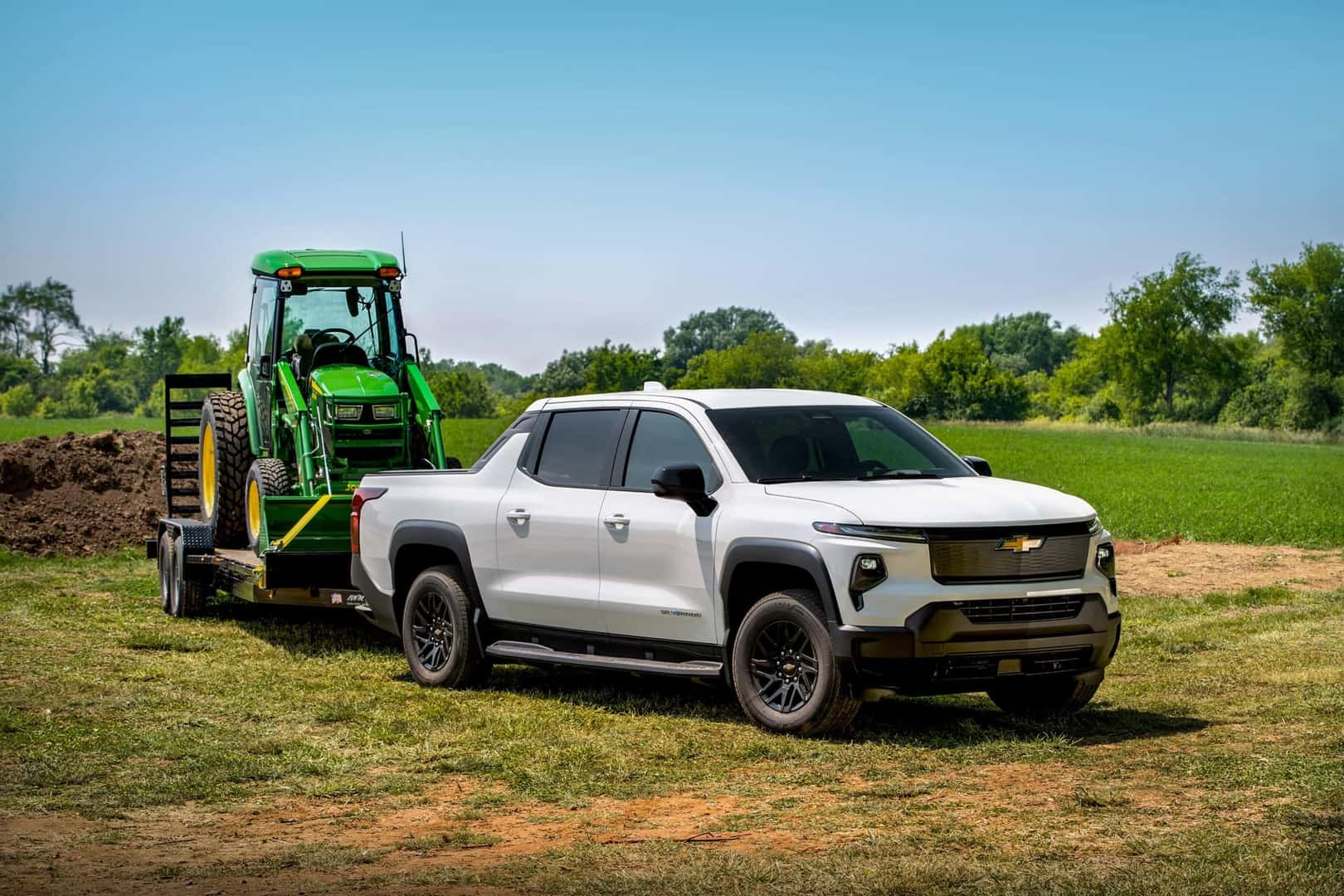 Summit White 2024 Chevrolet Silverado EV RST towing a tractor 
