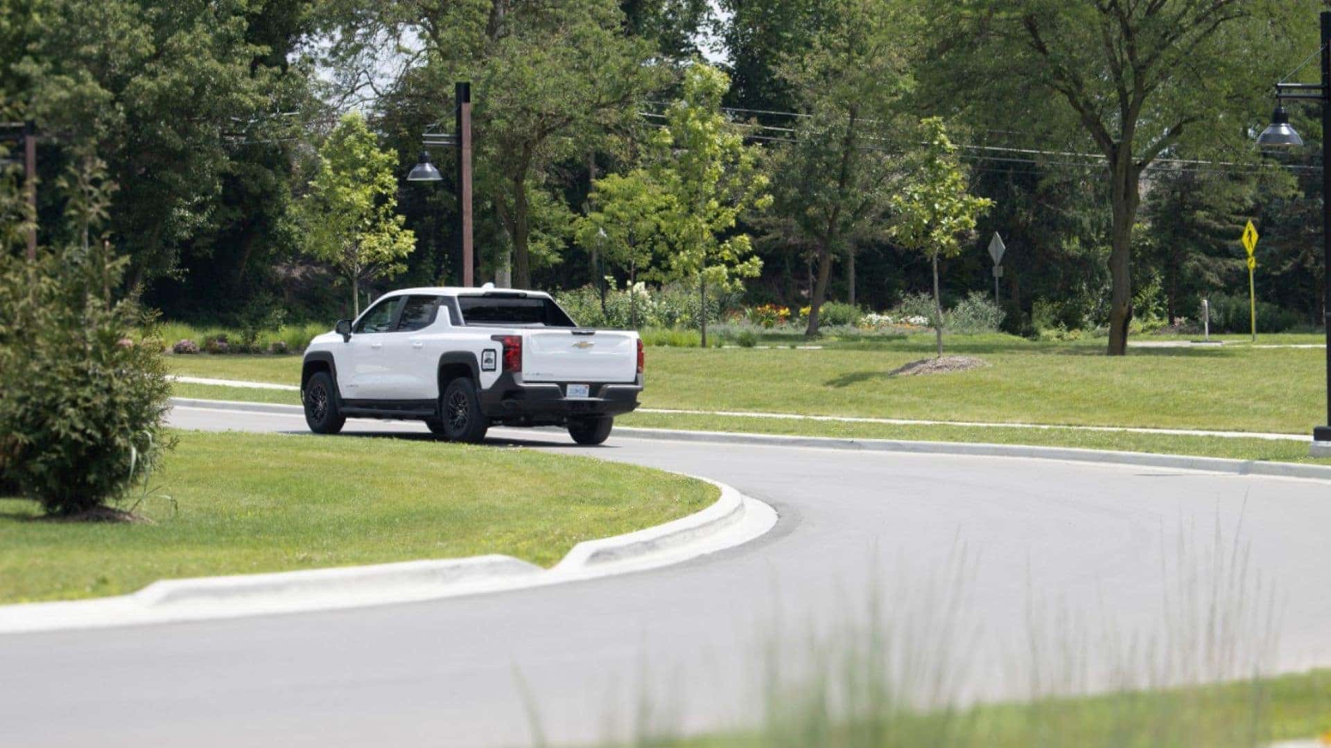 The Long-Range And Emission-Free EV Truck, The Chevrolet Silverado EV Departing From A Grassy Area To The Road