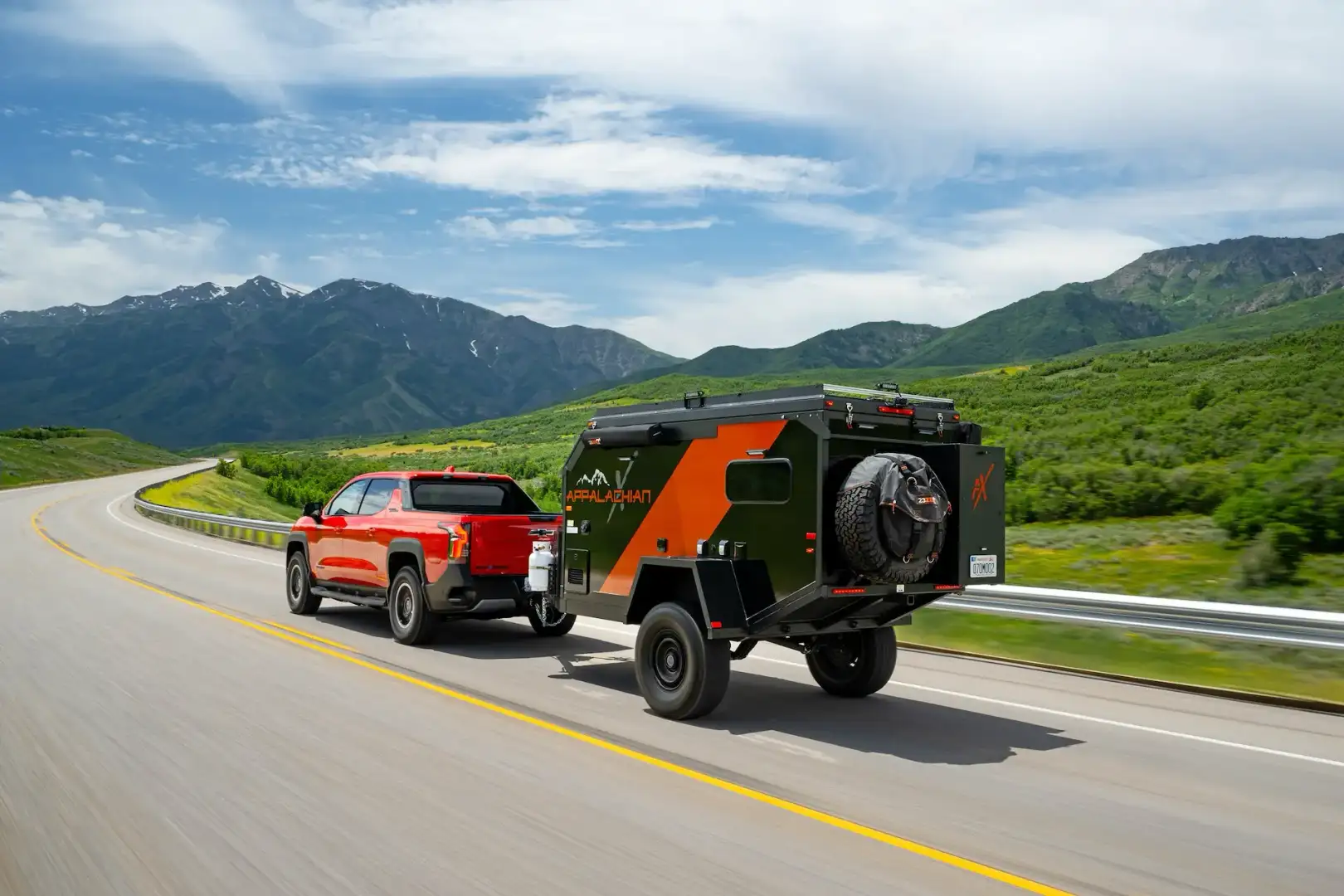 2026 Red Chevrolet Silverado EV Trail Boss towing on the road through mountains