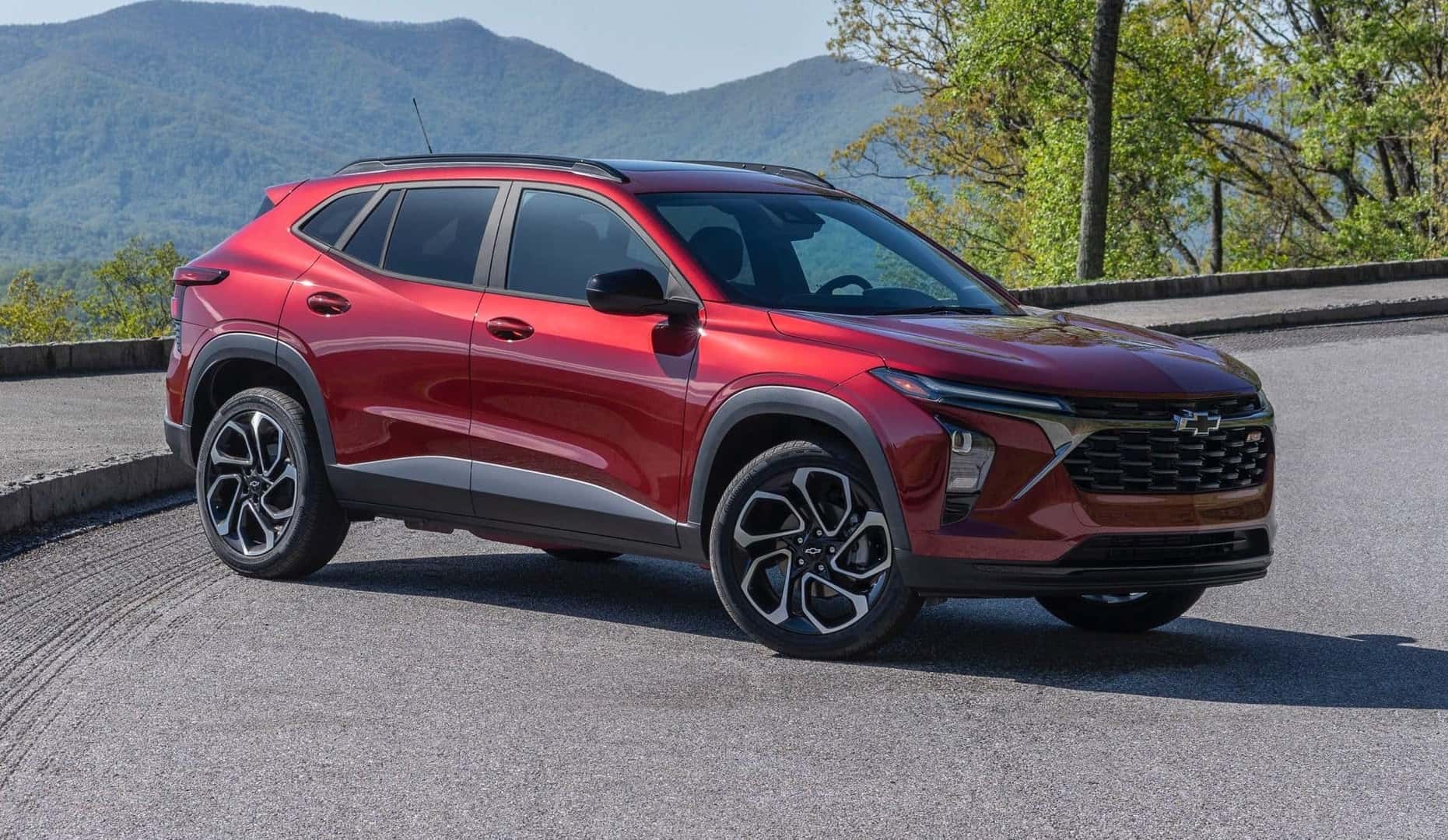 The Practical 2024 Chevrolet Trax, Parked In View Of Vast Mountains And High Trees.
