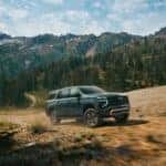 The Family-Friendly And Adventurous 2026 Chevrolet Suburban Driving off-Road Past Forests And Mountains