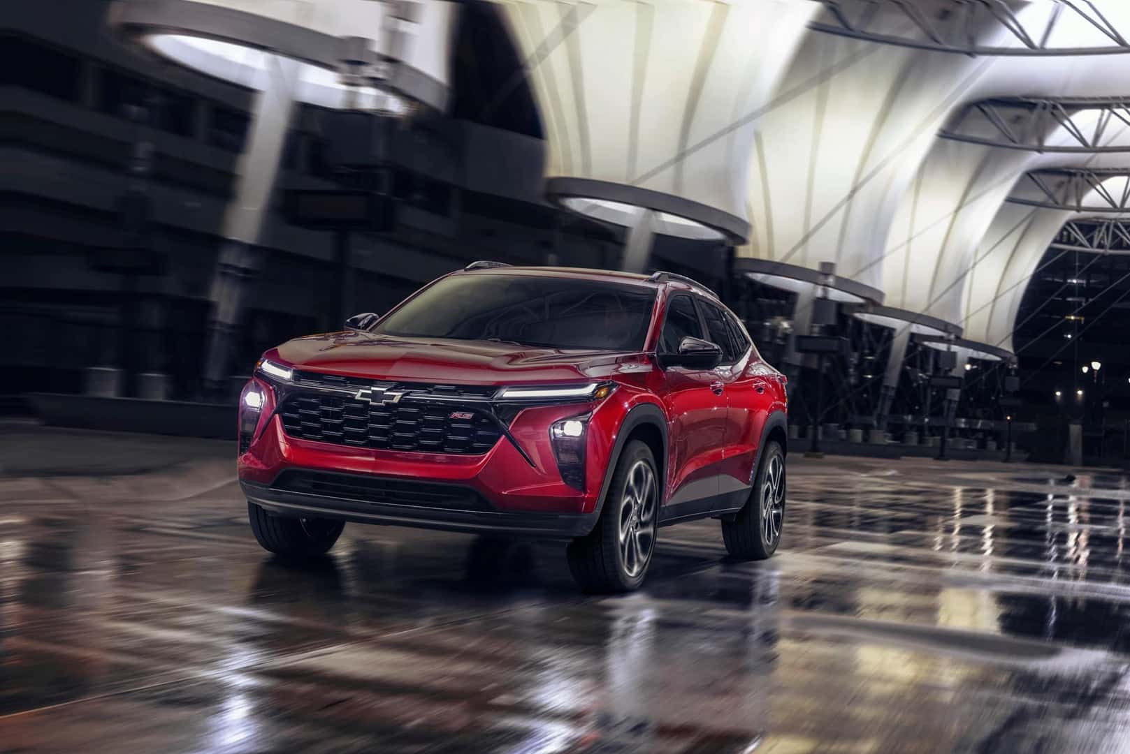 The Budget-Friendly And Affordable 2024 Chevrolet Trax's Red Exterior, Driving On A Wet Road With Grace And Style