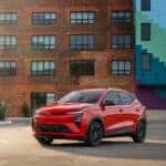 The Stylish Exterior Of The Spacious And Efficient Chevrolet Bolt EV, Parked In Front Of A Brick Building That Has A Mural