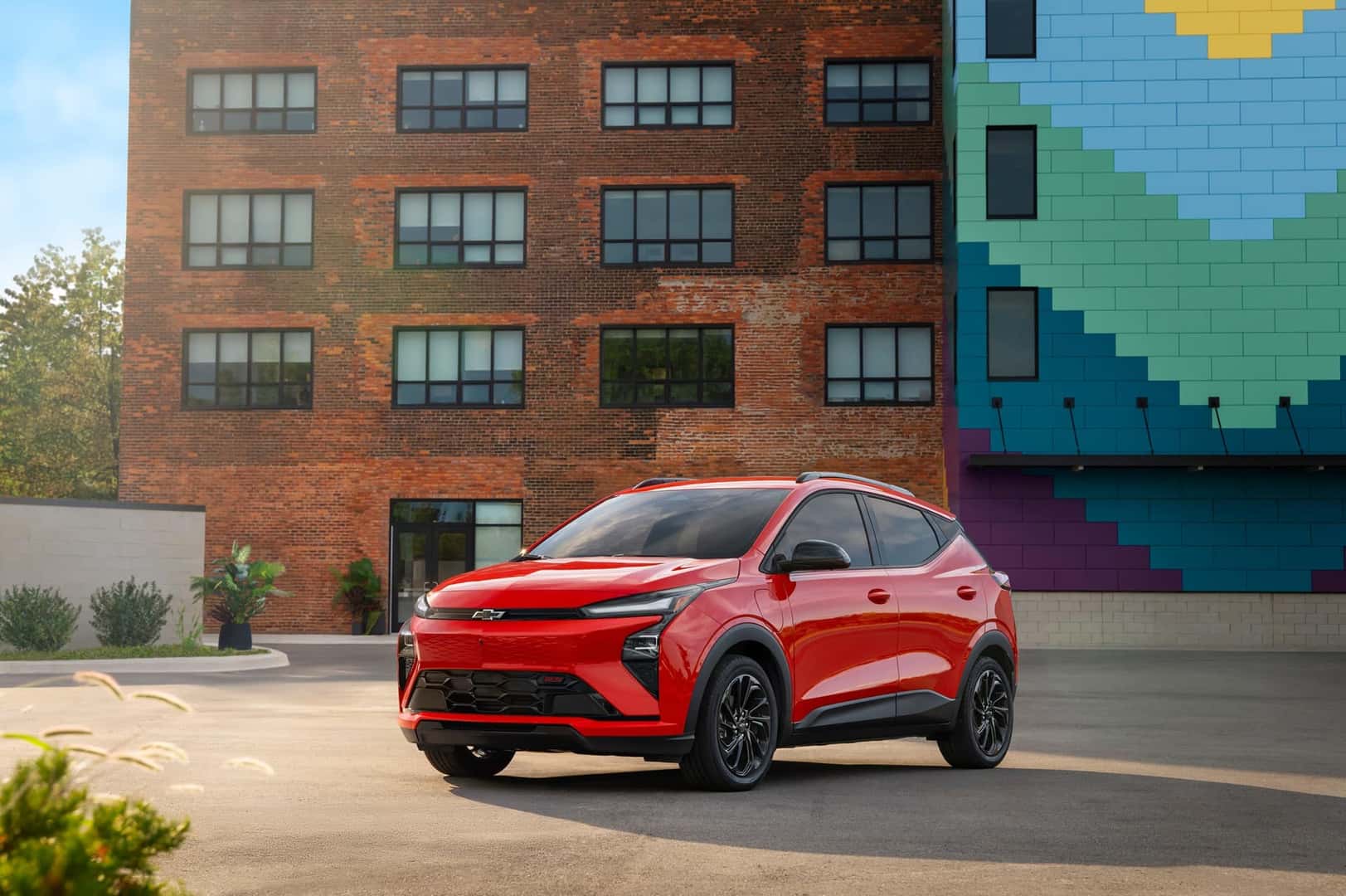 The Stylish Exterior Of The Spacious And Efficient Chevrolet Bolt EV, Parked In Front Of A Brick Building That Has A Mural