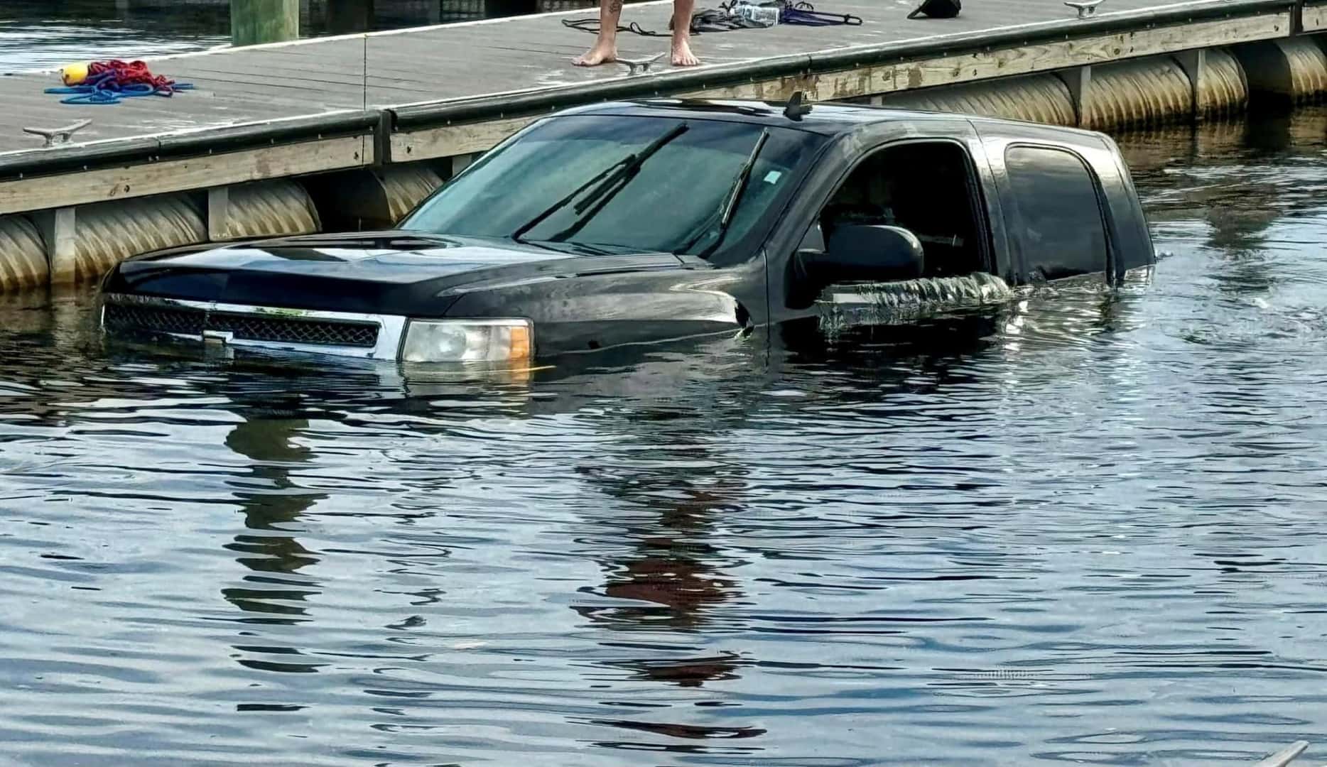 A Black Chevrolet Truck Submerged In A Lake's Water Due To A Driver Missing Multiple Steps